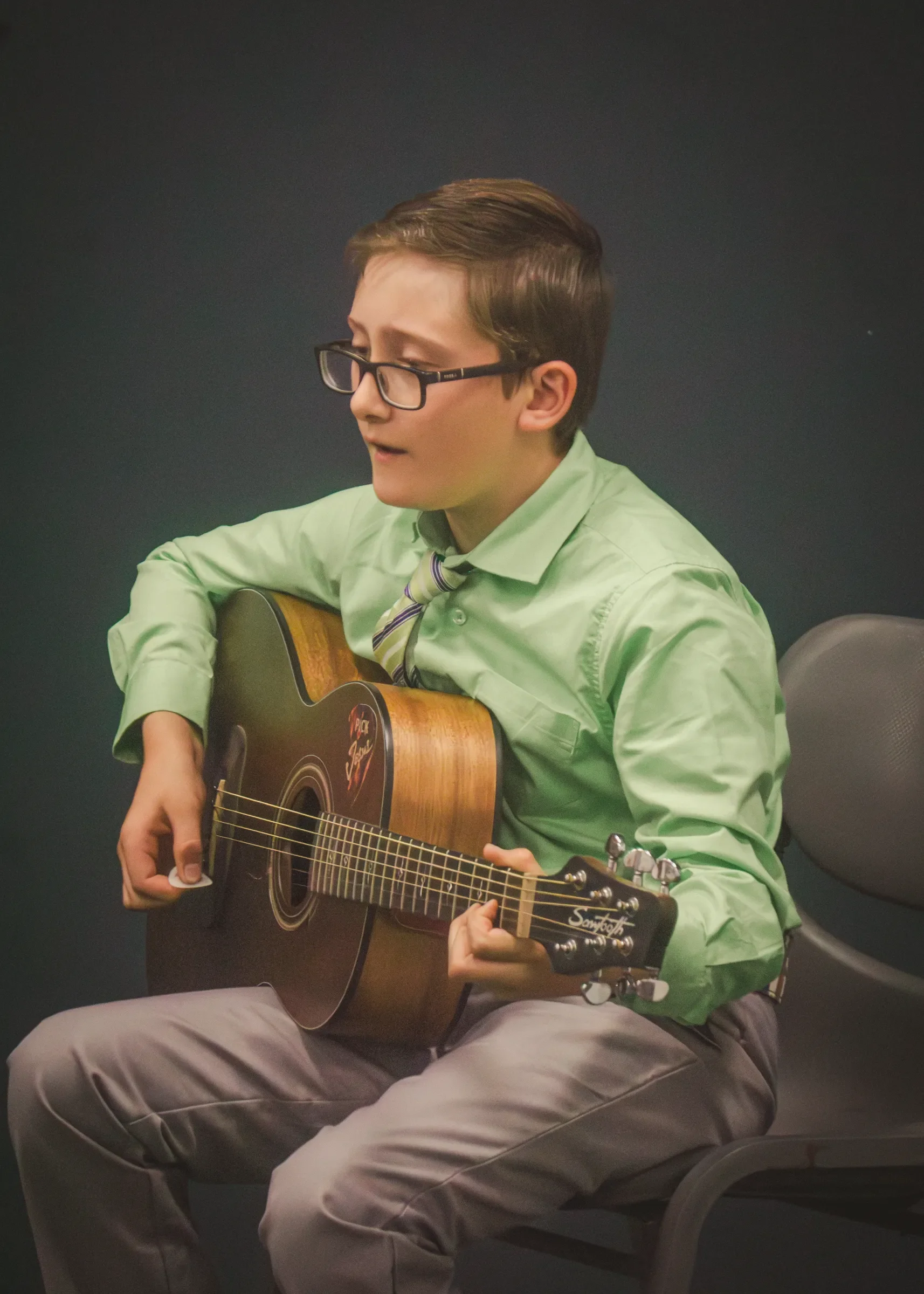 Student in green shirt playing guitar